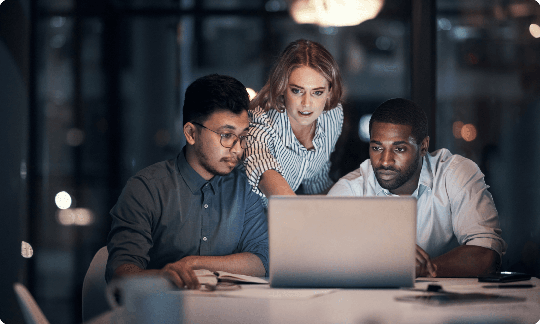 A group of employees at a laptop receiving a Dashlane AI phishing alert in the browser, protected from credential exposure before engaging with a fraudulent site.