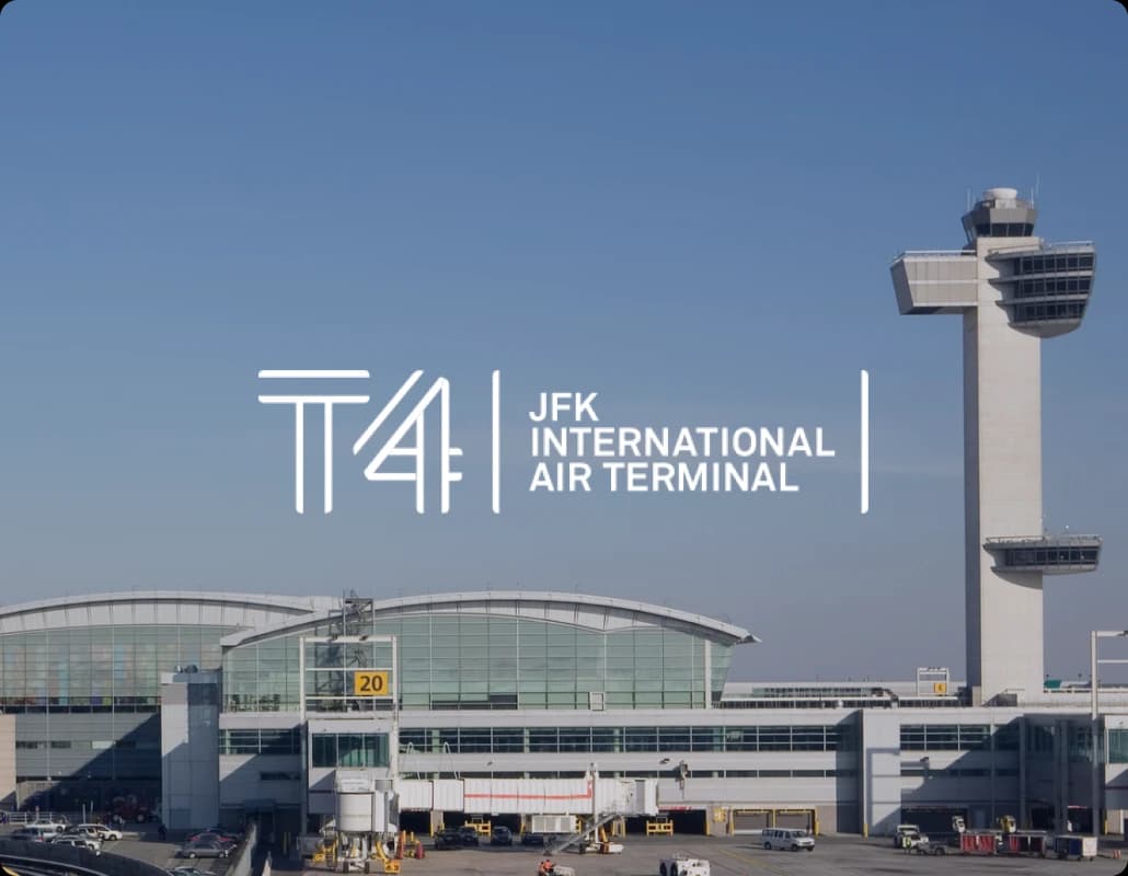 Exterior view of the JFK International Air Terminal building and control tower, featuring the Terminal 4 T4 logo.