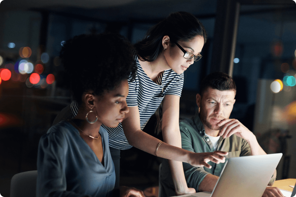 Three colleagues collaborate around a computer, representing Dashlane’s business password management product and how it secures access and boosts employee productivity.