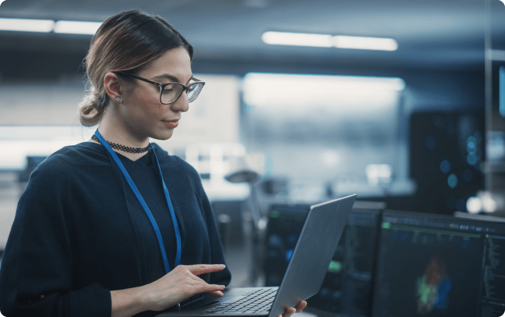 An IT admin works at her computer standing in a modern office.